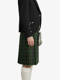 Person wearing a black blazer and green plaid kilt on a white background