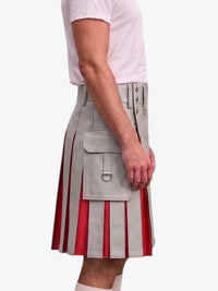 A side view of a model wearing a light gray faux-leather kilt with red vertical pleated stripes and silver buckle details, paired with a white t-shirt and white socks, against a plain white background.