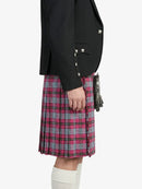 Person wearing a black blazer and pink plaid kilt on a white background