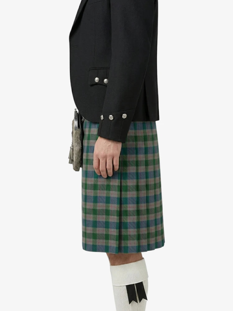 Person wearing a black jacket and green plaid kilt on a white background
