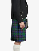 Person wearing a black blazer and green plaid kilt on a white background