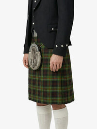 Person wearing a black jacket, green plaid kilt, and white knee-high socks on a white background