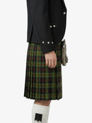 Person wearing a black jacket and green plaid kilt on a white background
