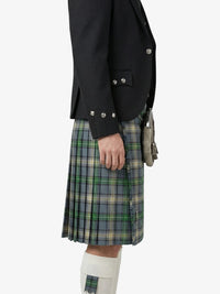 Person wearing a black jacket and plaid kilt on a white background