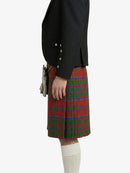 Person wearing a black jacket and red plaid kilt on a white background