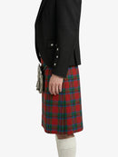 Person wearing a black jacket and red plaid kilt on a white background