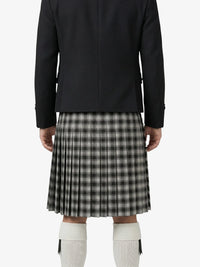 Person wearing a black jacket and plaid kilt on a white background