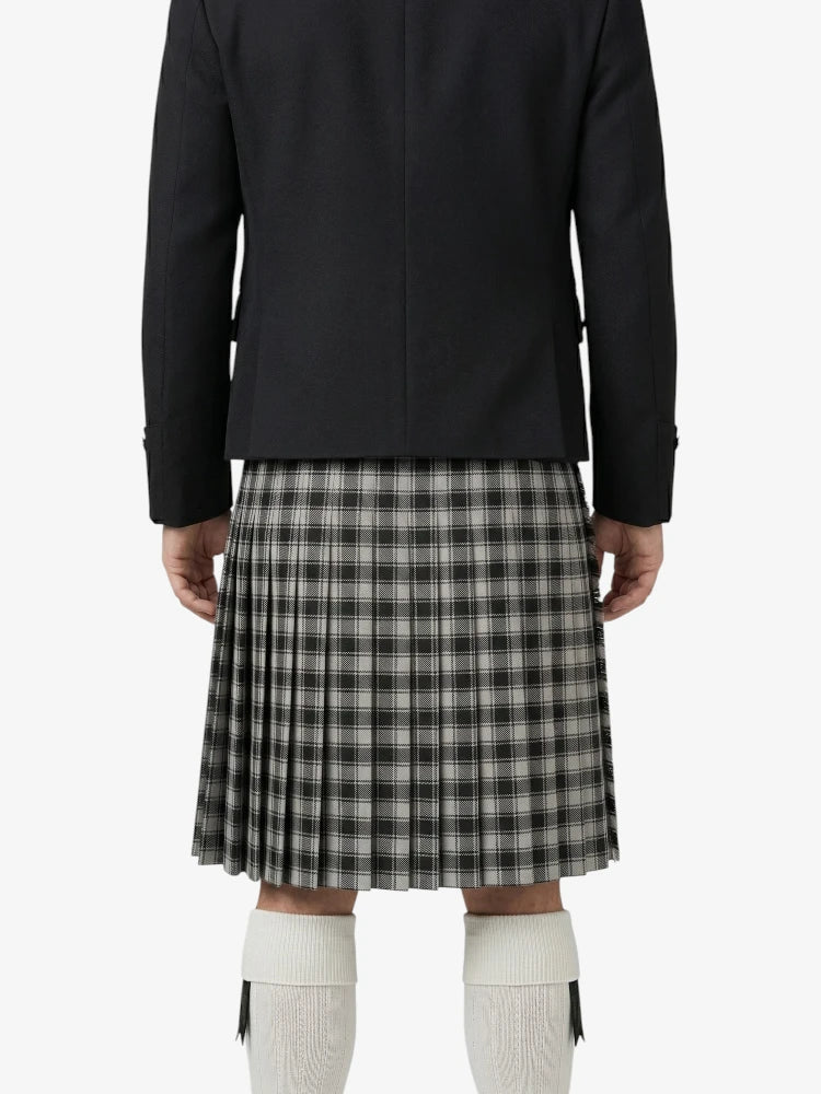 Person wearing a black jacket and plaid kilt on a white background