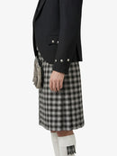 Person wearing a black blazer and plaid kilt on a white background