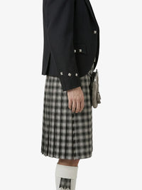 Person wearing a black jacket and plaid kilt on a white background