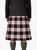 Person wearing a black jacket and plaid kilt on a white background