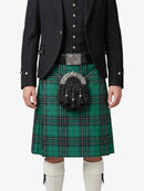Person wearing a green plaid kilt with a black jacket on a white background