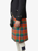 Person wearing a black jacket and a colorful plaid kilt on a white background