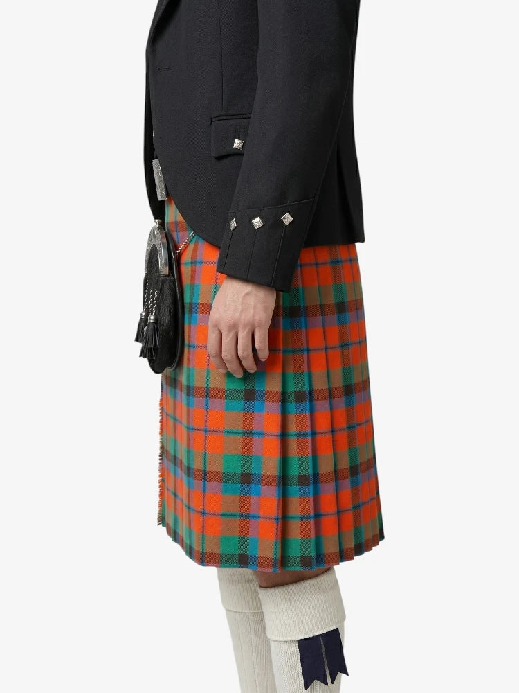 Person wearing a black jacket and a colorful plaid kilt on a white background