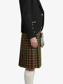 Person wearing a black blazer and plaid kilt on a white background