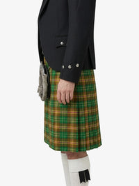 Person wearing a black jacket and green plaid kilt on a white background