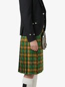 Person wearing a black jacket and green plaid kilt on a white background
