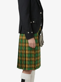 Person wearing a black jacket and green plaid kilt on a white background