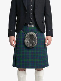 Person wearing a green plaid kilt with a dark jacket on a white background