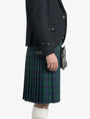 Person wearing a dark jacket and green plaid kilt on a white background
