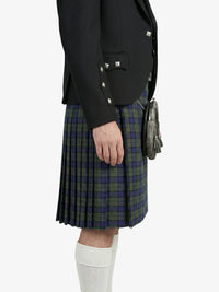 Person wearing a black blazer, green plaid kilt, and white knee-high socks on a white background