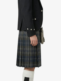 Person wearing a black jacket and plaid kilt on a white background