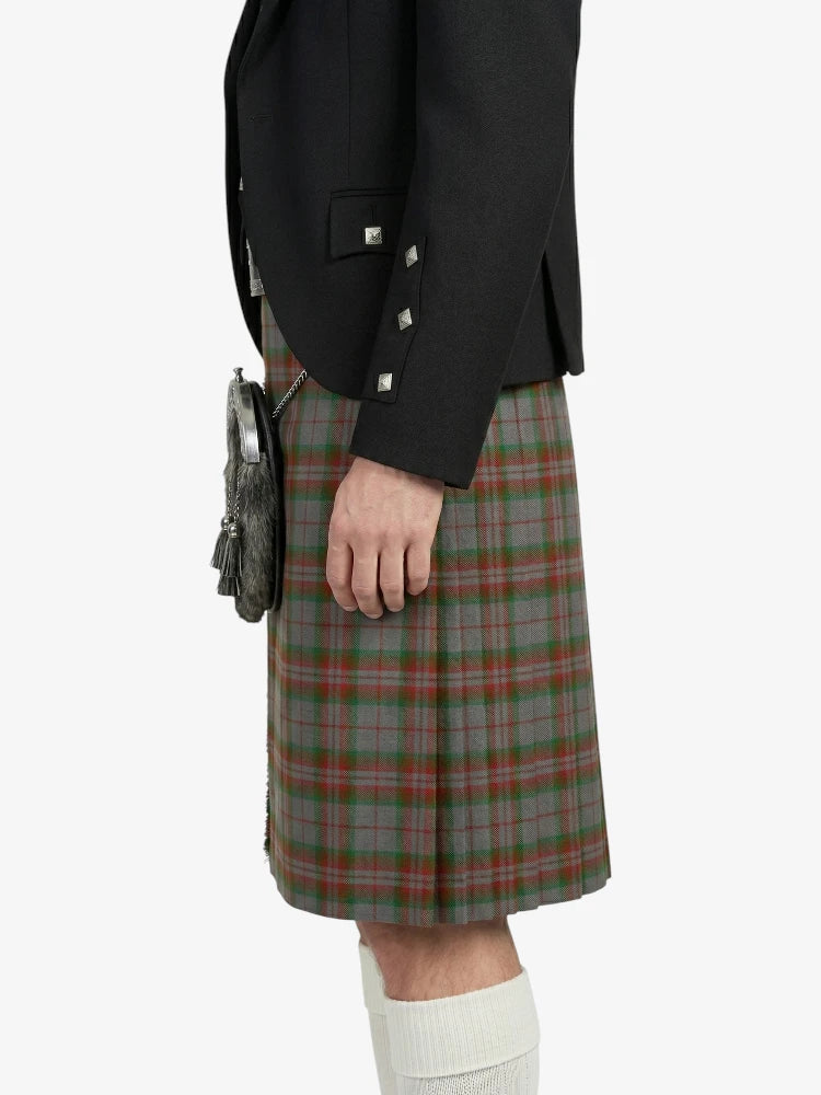 Person wearing a black jacket and green plaid kilt on a white background