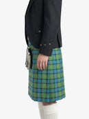 Person wearing a black jacket and green plaid kilt on a white background