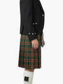 Person wearing a black jacket and green plaid kilt on a white background