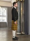Man wearing a black jacket and yellow plaid kilt in an elegant interior setting.