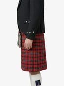 Person wearing a black blazer and red plaid kilt on a white background