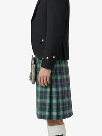 Person wearing a black blazer and green plaid kilt on a white background