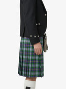 Person wearing a black jacket and green plaid kilt on a white background