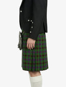 Person wearing a black jacket and green plaid kilt on a white background