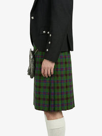 Person wearing a black jacket and green plaid kilt on a white background