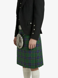 Person wearing a black jacket and green plaid kilt on a white background