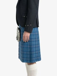 Person wearing a dark jacket and blue plaid kilt on a white background