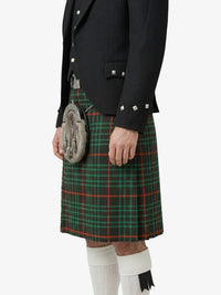 Person wearing a black jacket and green plaid kilt on a white background