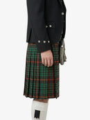 Person wearing a black jacket and green plaid kilt on a white background