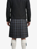 Person wearing a black jacket and plaid kilt on a white background