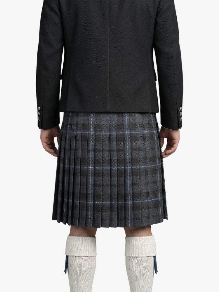 Person wearing a black jacket and plaid kilt on a white background