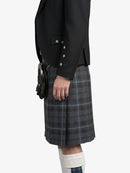 Person wearing a black blazer and plaid kilt on a white background
