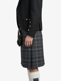 Person wearing a black blazer and plaid kilt on a white background