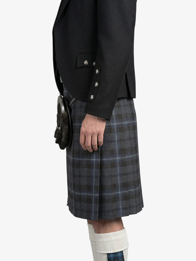 Person wearing a black blazer and plaid kilt on a white background
