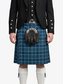 Person wearing a blue plaid kilt with a black jacket on a white background