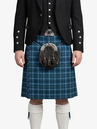Person wearing a blue plaid kilt with a black jacket on a white background