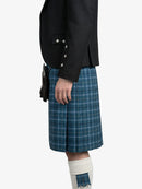 Person wearing a dark jacket and blue plaid kilt on a white background