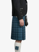 Person wearing a blue plaid kilt with a black jacket on a white background