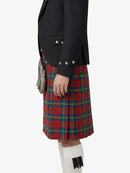 Person wearing a black jacket and red plaid kilt on a white background