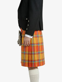 Person wearing a black jacket and colorful plaid kilt on a white background